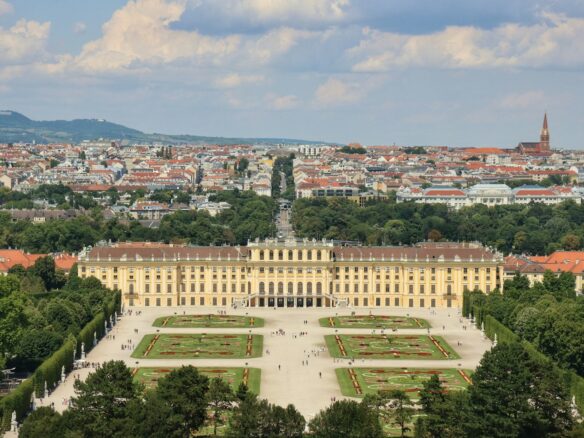 a large building with a courtyard and trees in front of it with Schönbrunn Palace in the background