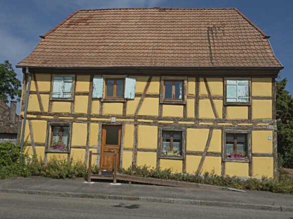 a yellow house with a brown roof and windows