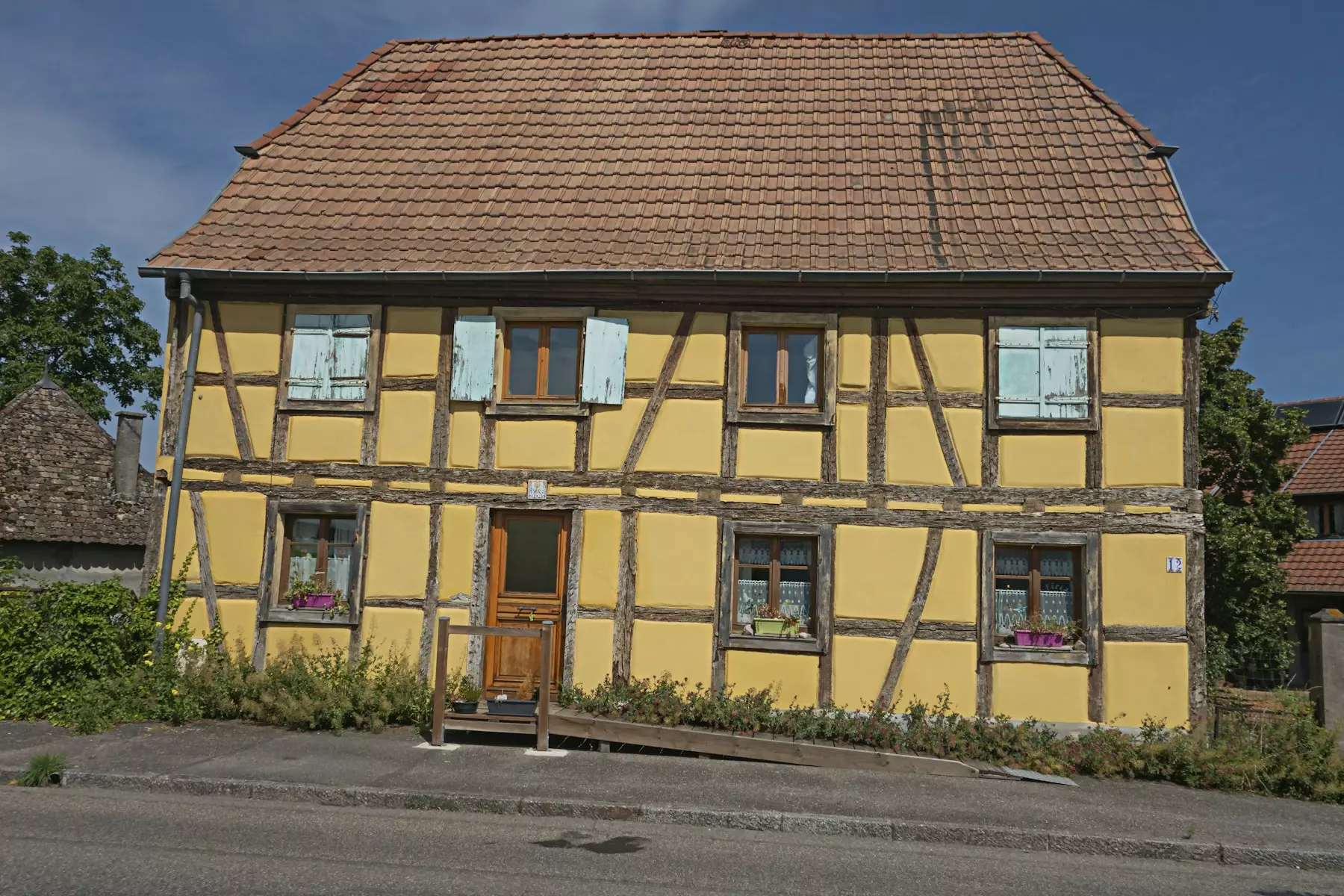 a yellow house with a brown roof and windows