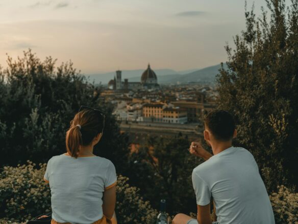 woman and man wearing white shirt while sitting near green trees during daytime