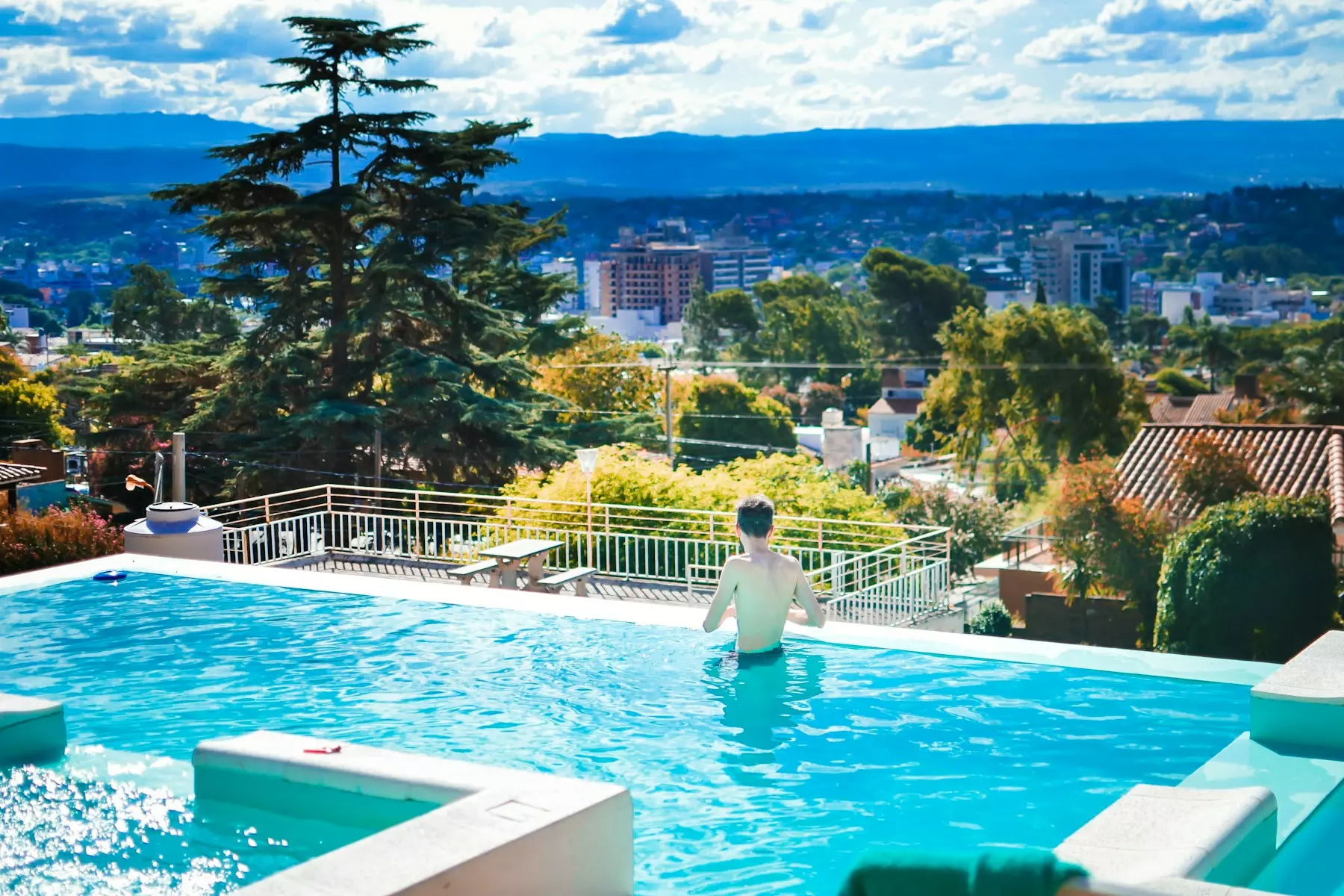 a person standing in a swimming pool with a view of a city