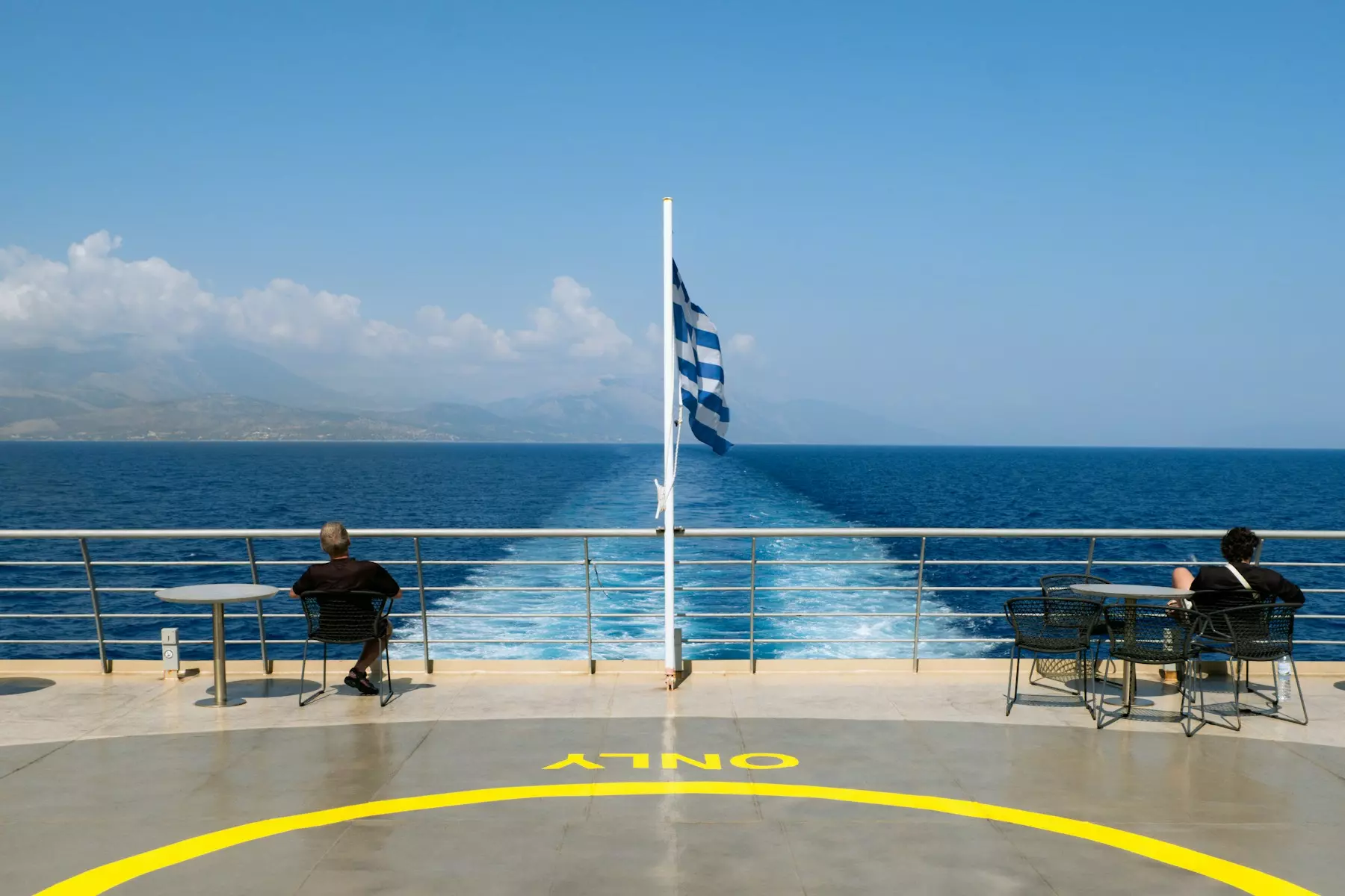Two people sitting on a bench on a cruise ship
