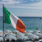 a large italian flag flying over a beach filled with umbrellas
