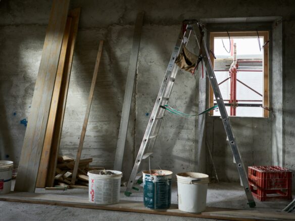 a ladder and buckets of paint in a room under construction