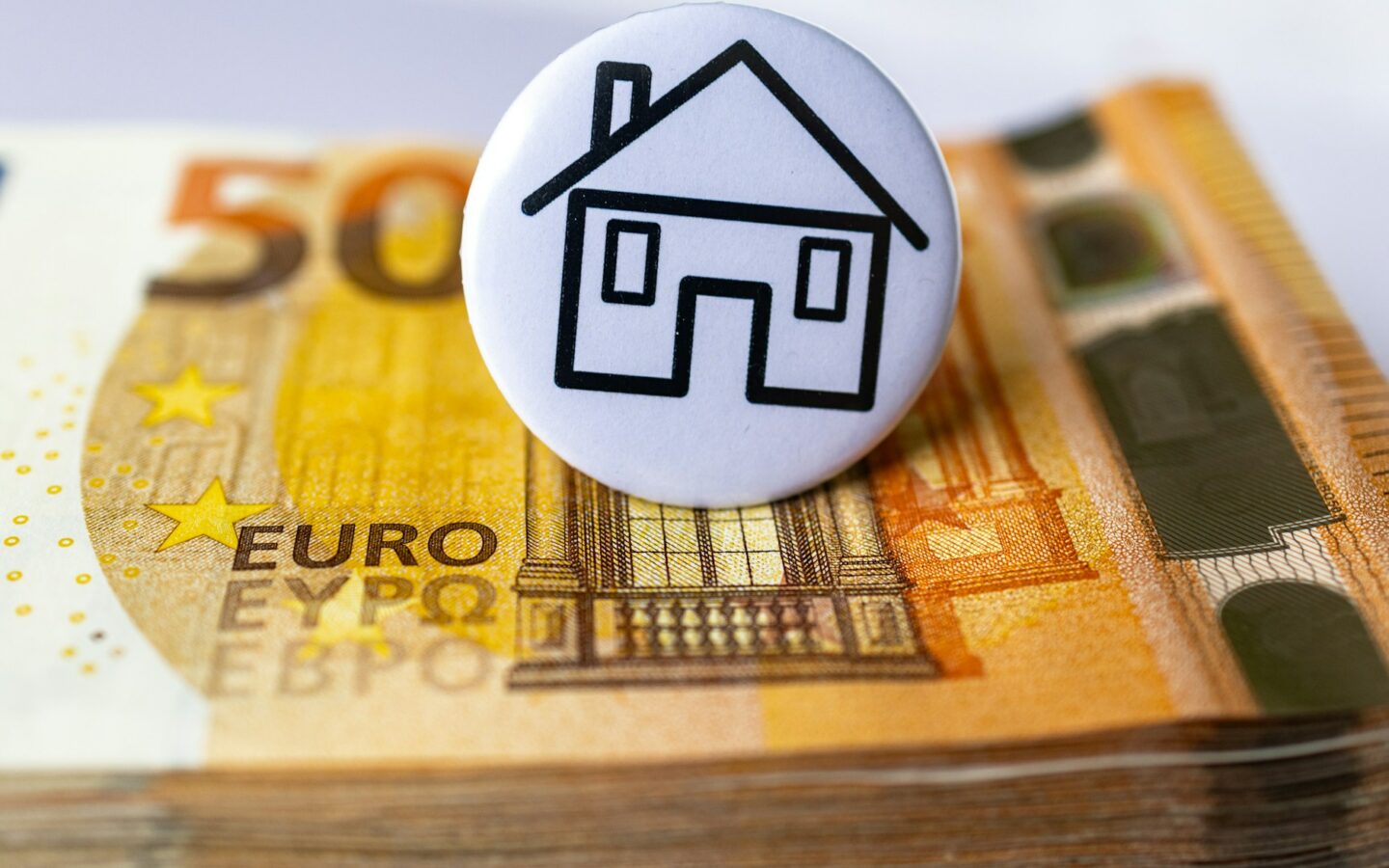 a button with a house on top of a stack of money