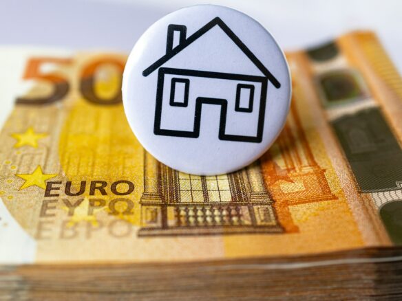 a button with a house on top of a stack of money