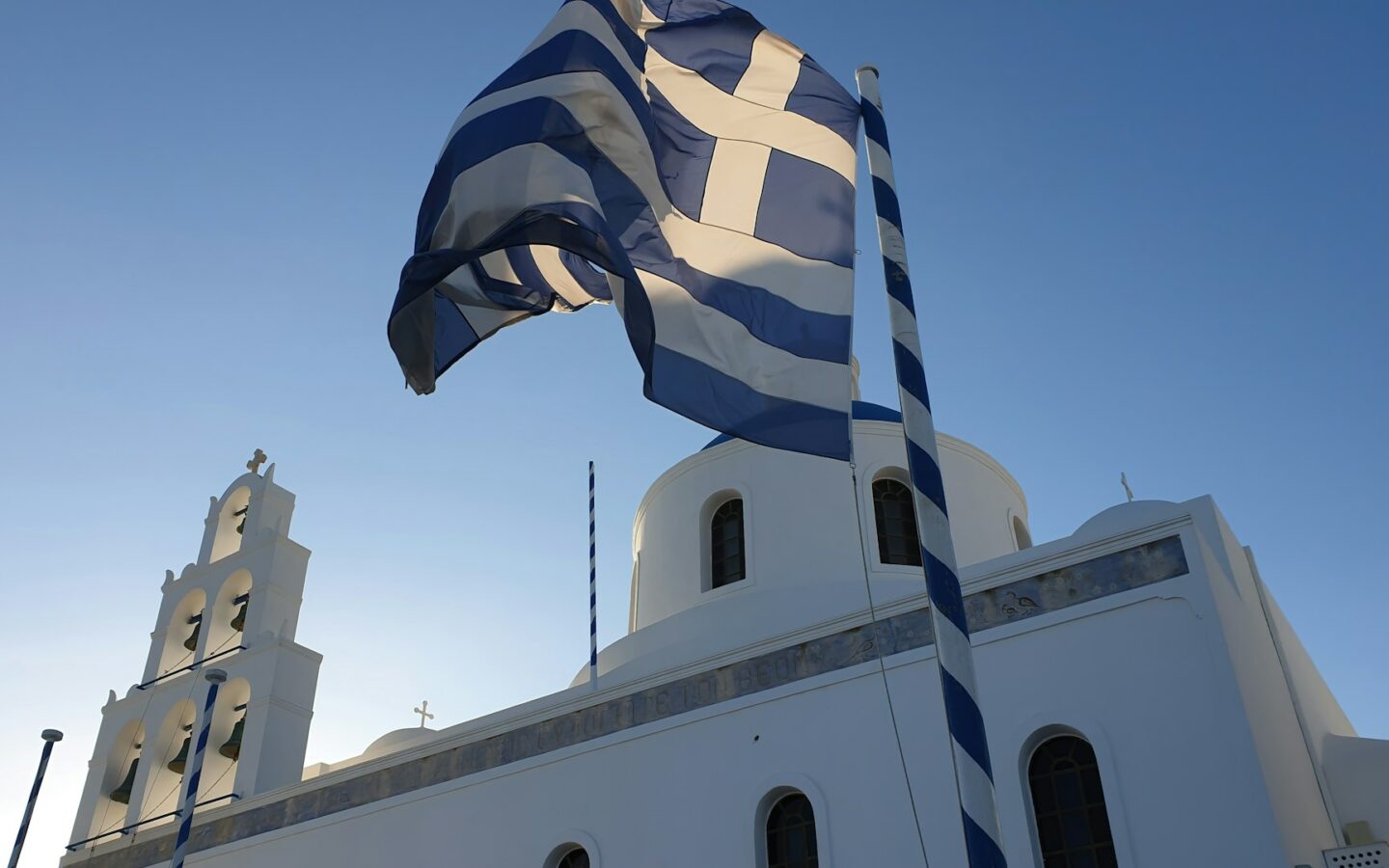 a large greek flag flying in front of a church