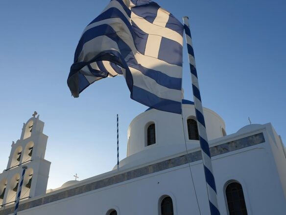 a large greek flag flying in front of a church