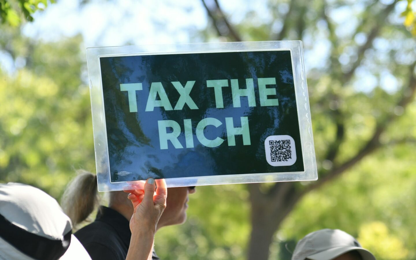 Person holds sign that says "tax the rich"
