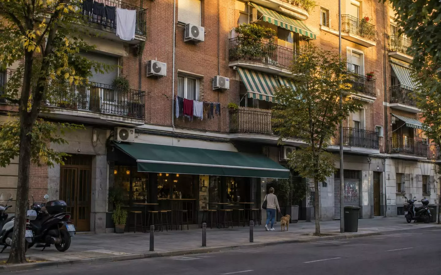 A Madrid apartment block with iron balconies, laundry and awnings in golden evening light (illustration)