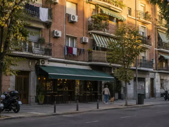 A Madrid apartment block with iron balconies, laundry and awnings in golden evening light (illustration)