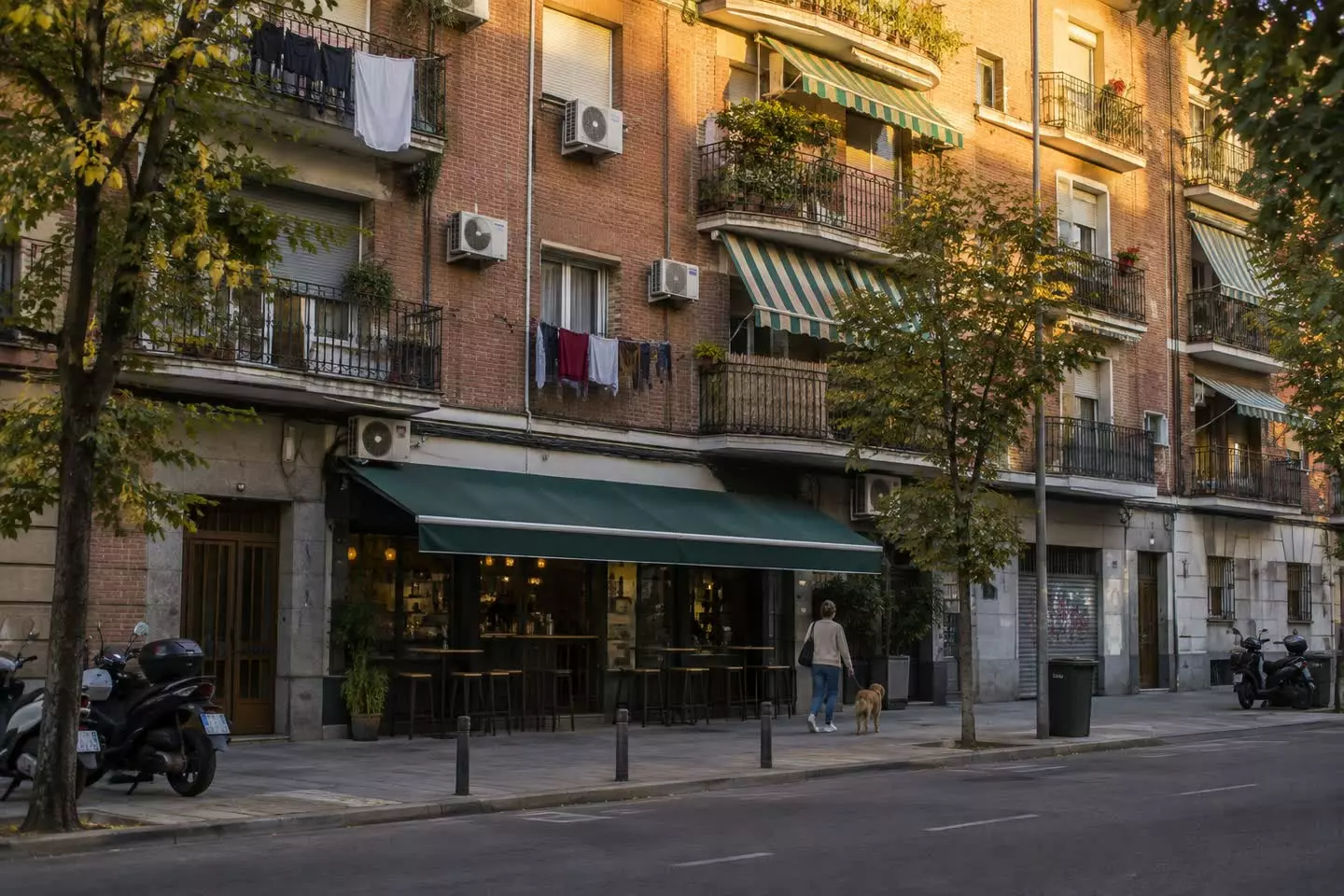 A Madrid apartment block with iron balconies, laundry and awnings in golden evening light (illustration)