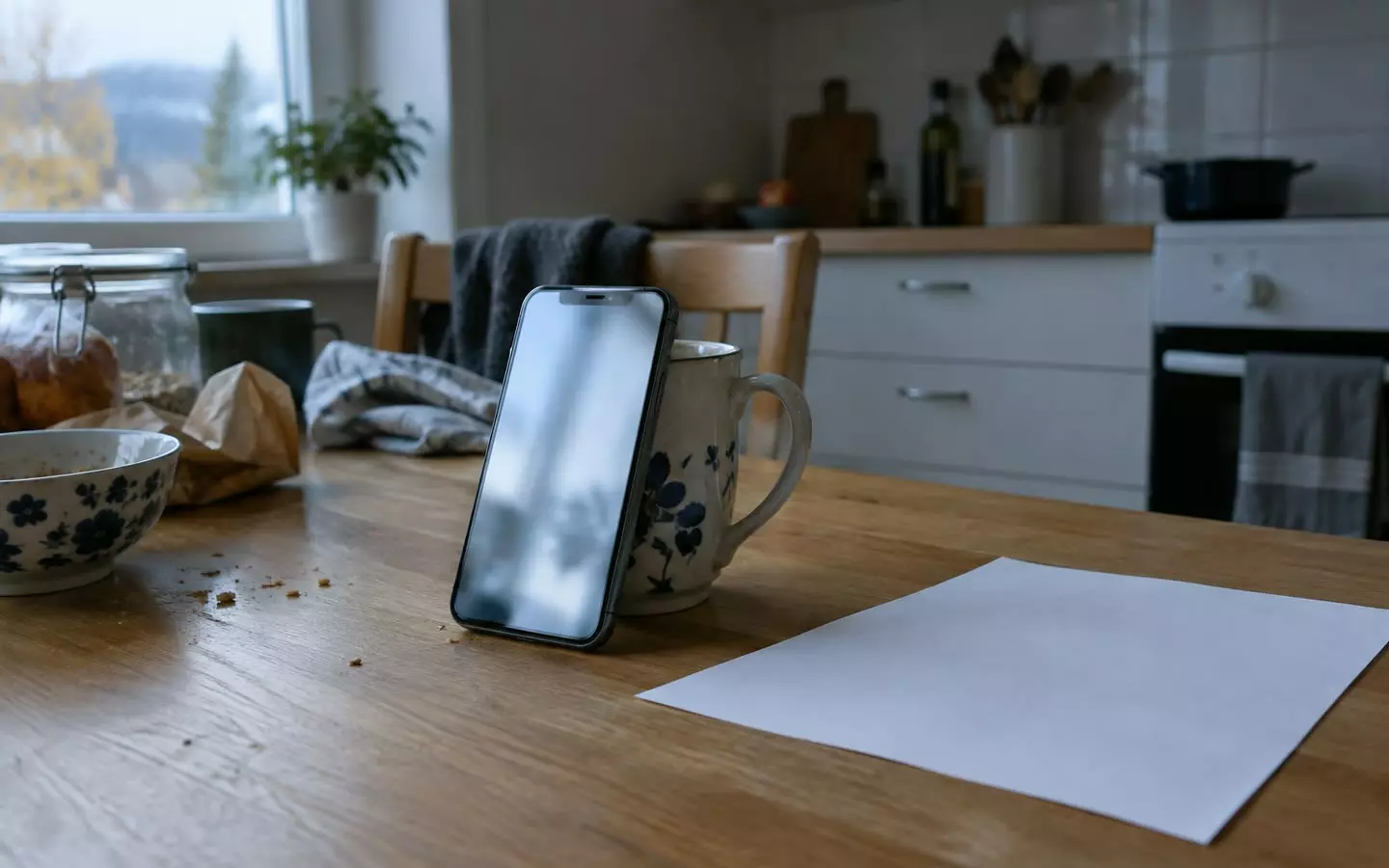 A phone playing a blurred video beside a printed sheet on a Norwegian kitchen table (illustration)