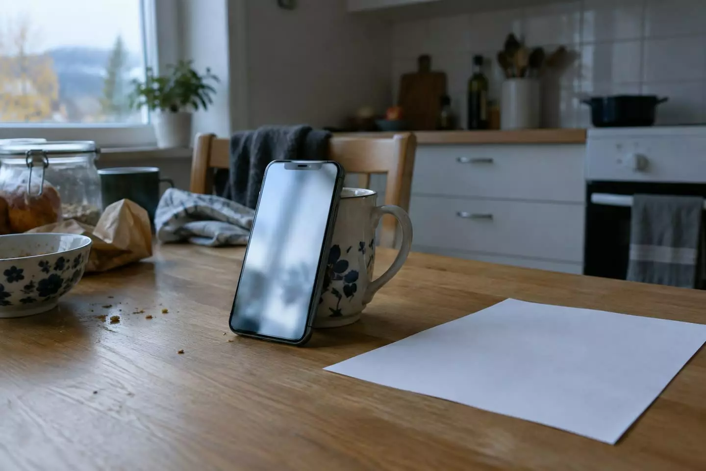 A phone playing a blurred video beside a printed sheet on a Norwegian kitchen table (illustration)