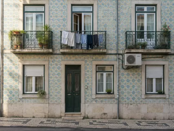 A pastel apartment building with azulejo tiles and wrought-iron balconies on a Lisbon street (illustration)