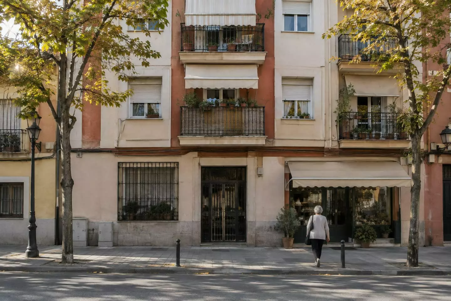 A residential street of mid-rise apartment buildings with iron balconies, persianas and awnings in Madrid on a mild early autumn morning (illustration)