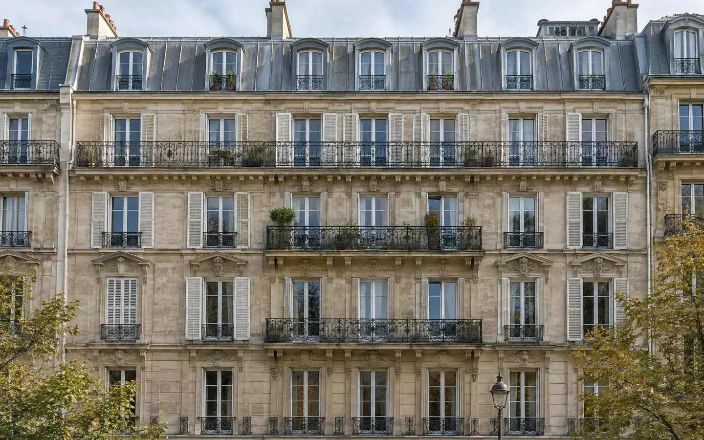 Die Fassade eines Wohnhauses aus der Haussmann-Ära mit schmiedeeisernen Balkonen und hohen Fensterläden an einer Pariser Straße im Frühherbst (Illustration)