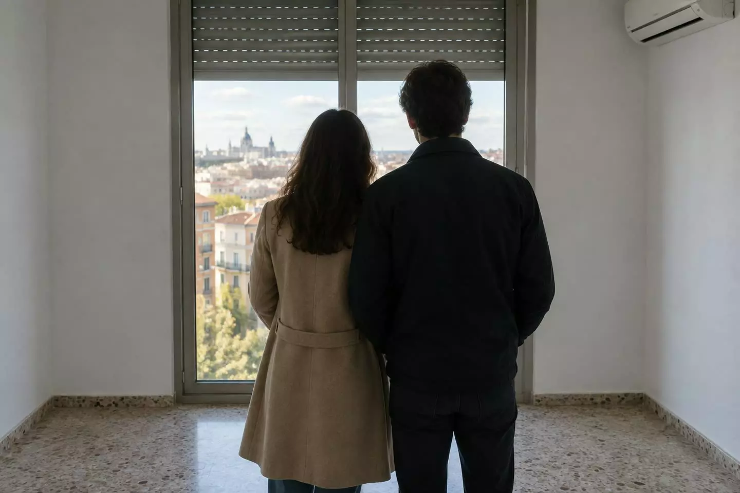 A couple looking out over the city from the window of an empty flat in Madrid, Spain, in early autumn (illustration)